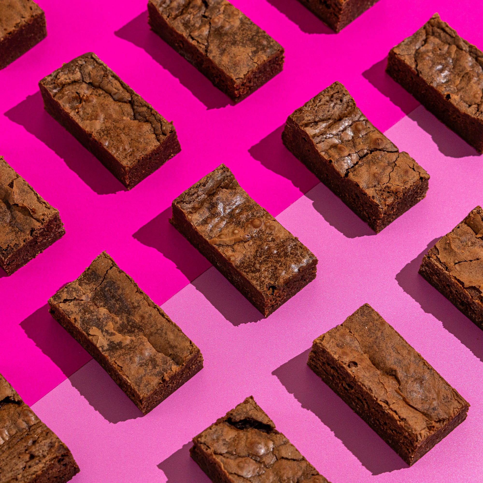 Classic fudgy plain brownies on a pink background