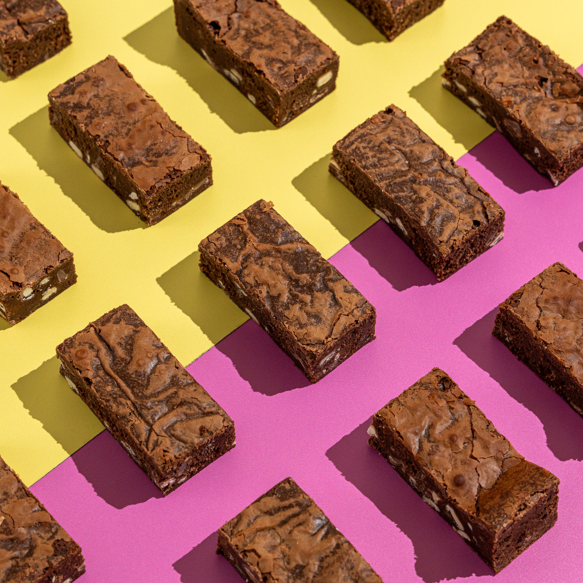 Fudgy triple chocolate brownie with white chocolate chunks on a yellow and lilac background.