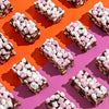 Marshmallow topped rocky road slices on an orange and lilac background